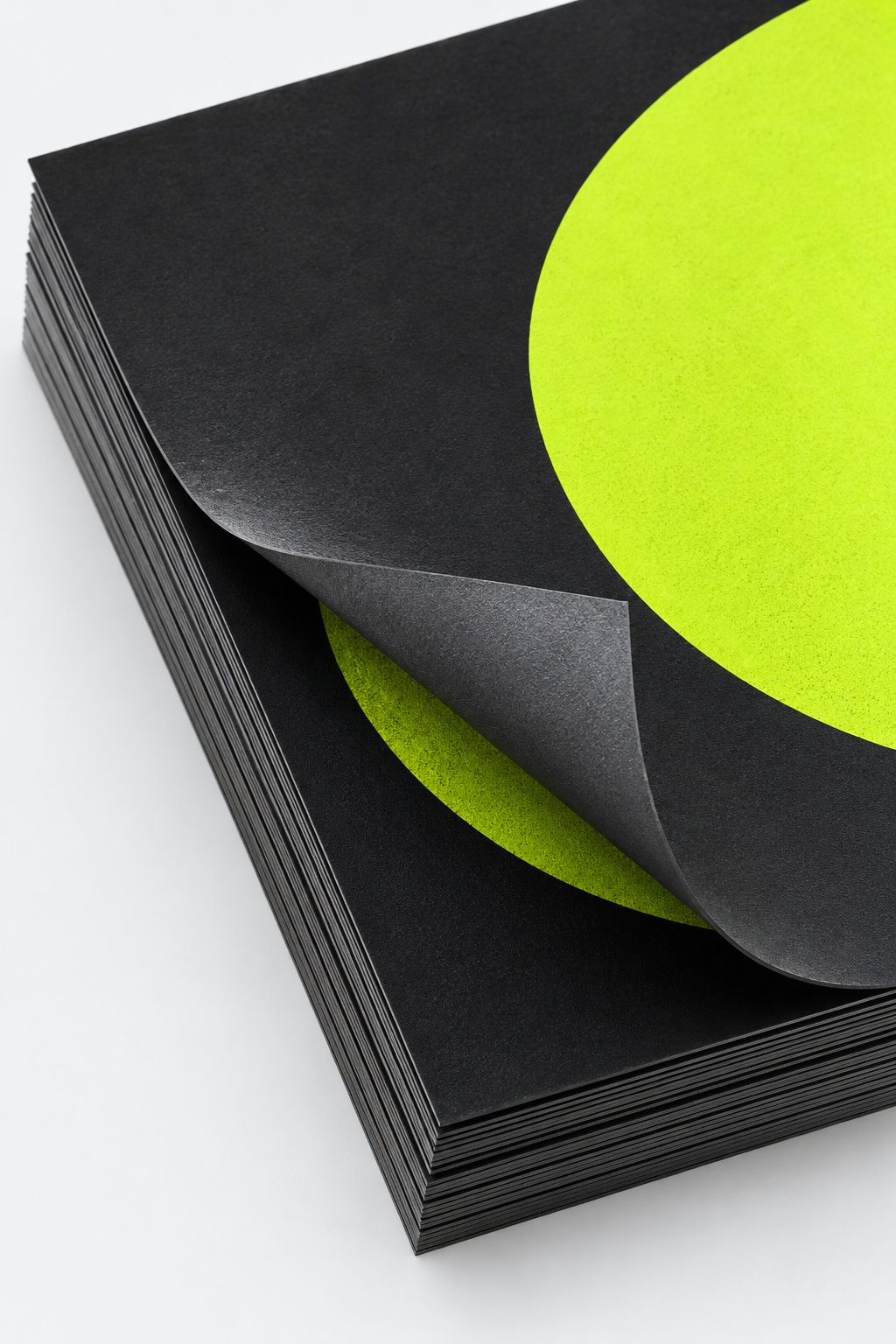 Close up of screen-printed posters with an acid lime circle segment on graphite stock